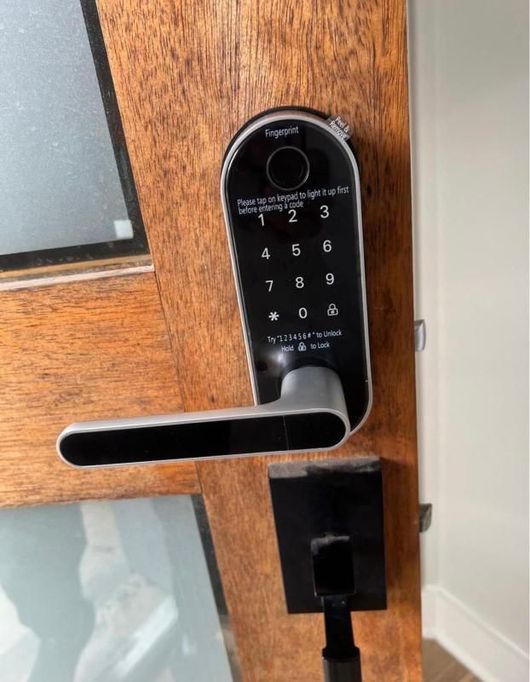 Digital door lock with keypad and lever handle on a wooden door