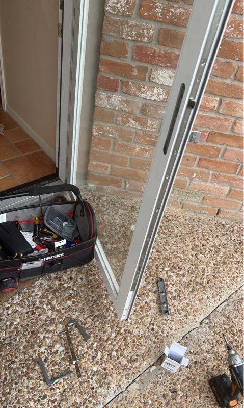 Open toolbox and scattered tools beside a partially installed white door by a brick wall.