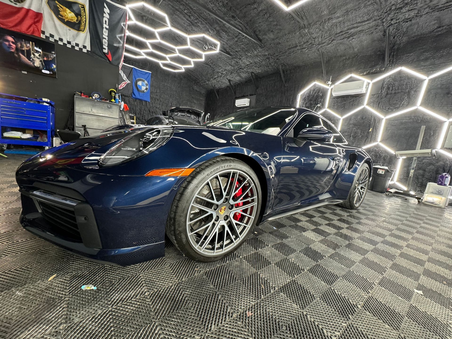 A blue porsche 911 turbo s is parked in a garage.