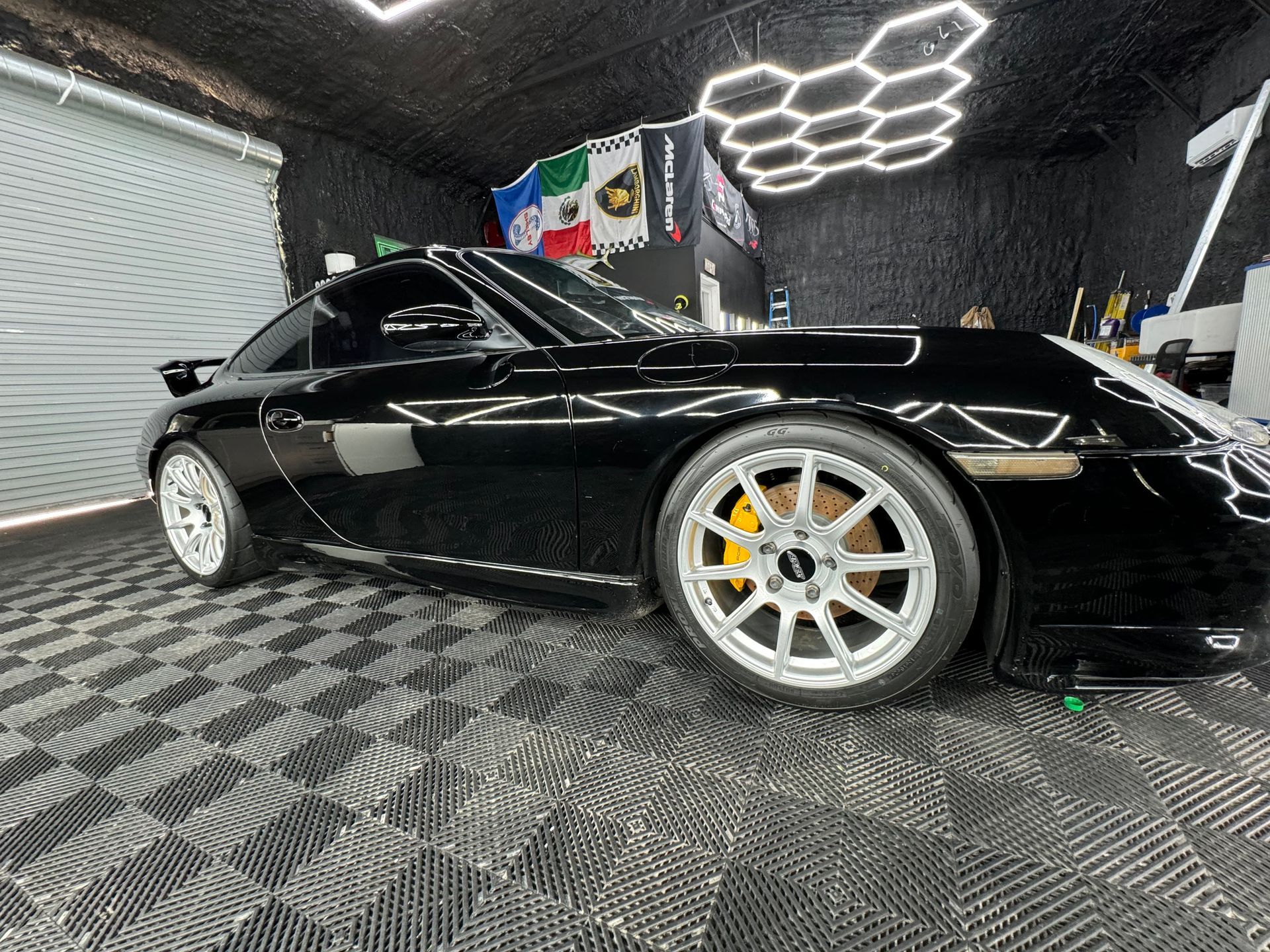 A black sports car is parked in a garage.