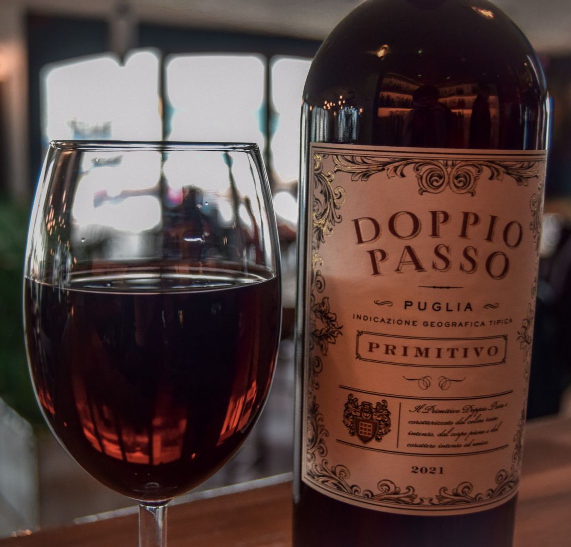 Doppio Passo red wine bottle with a half-full glass next to it.