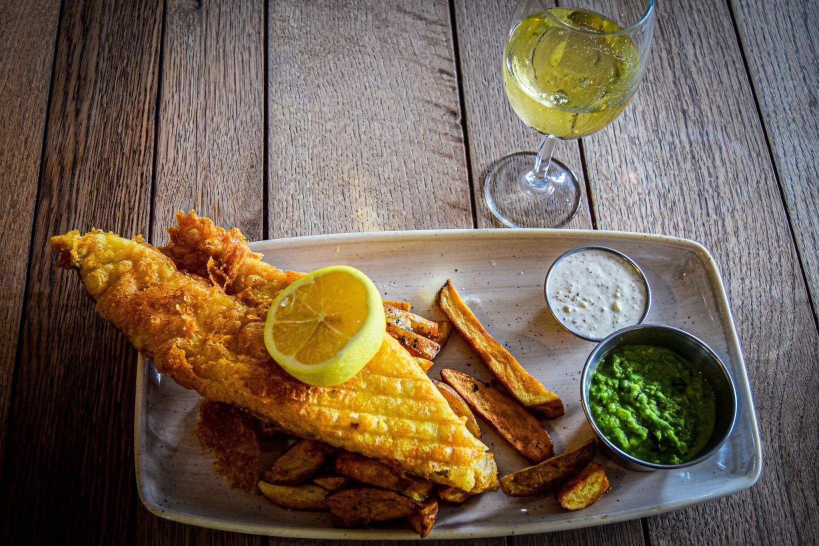 Fish and chips dish with lemon and mushy peas.