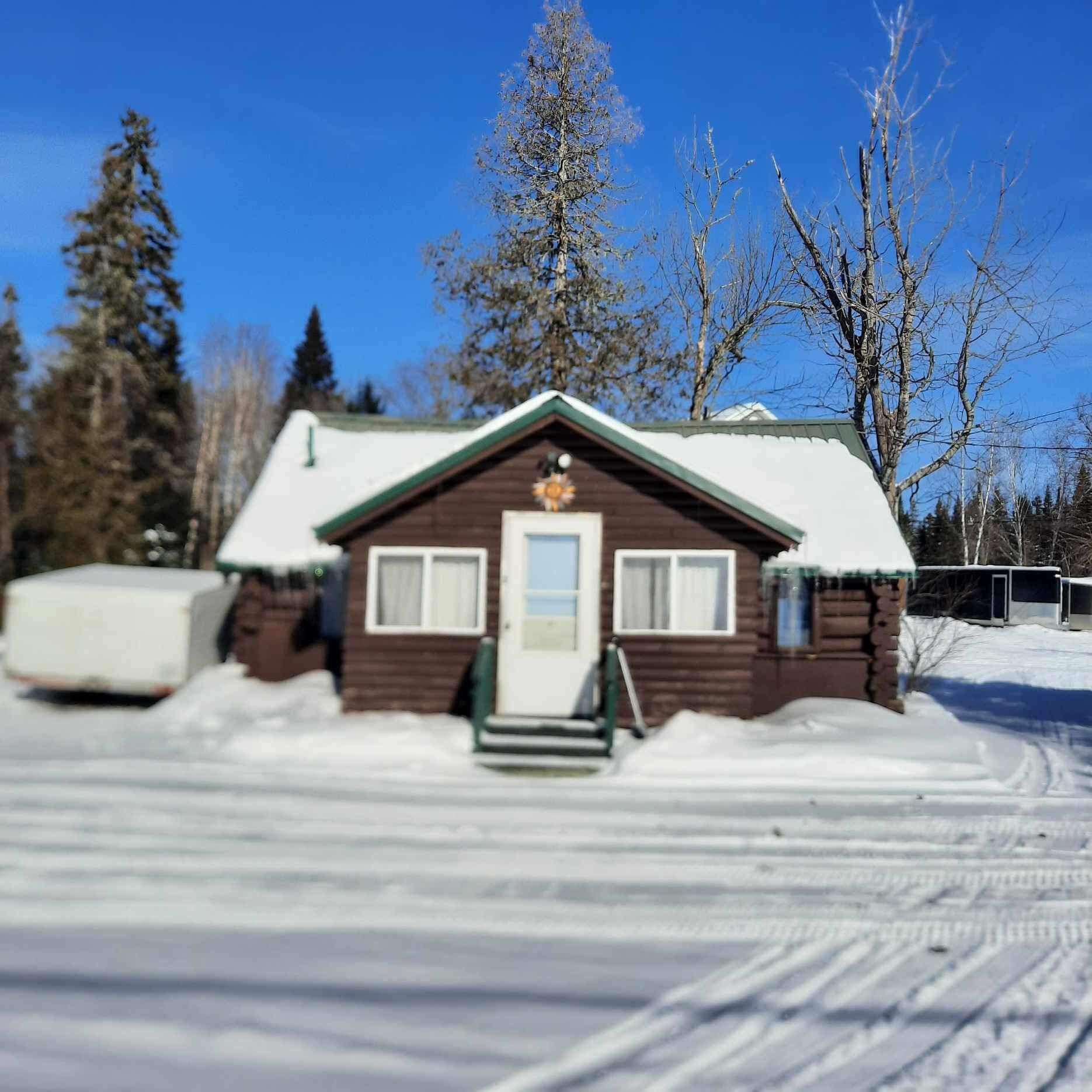 a small log cabin in the middle of a snowy field