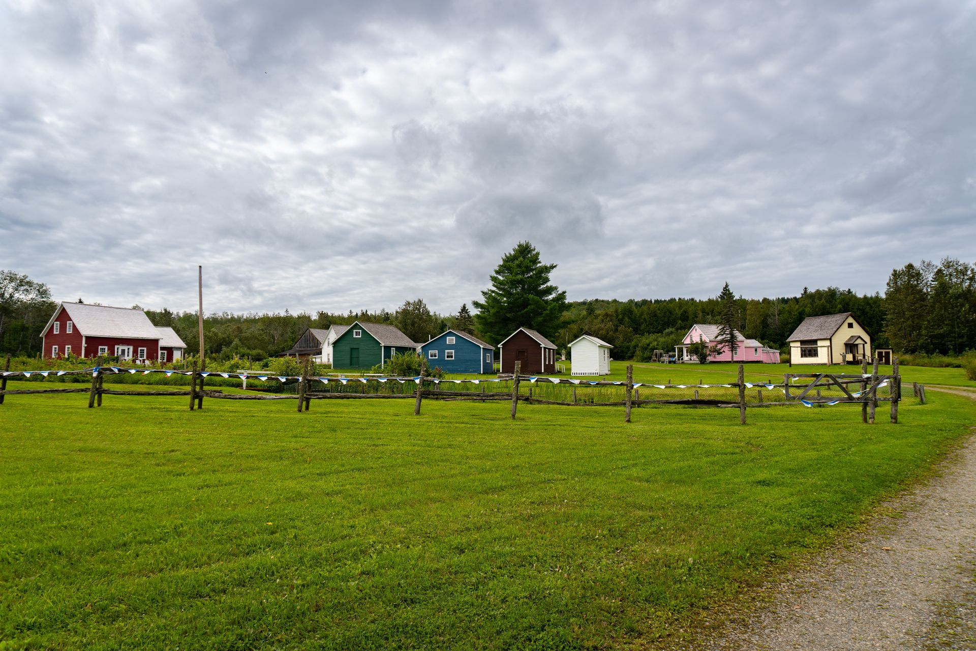 a grassy field with a fence and houses in the background