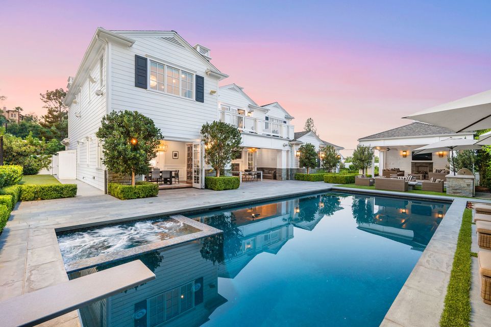 White house with pool and patio at dusk.