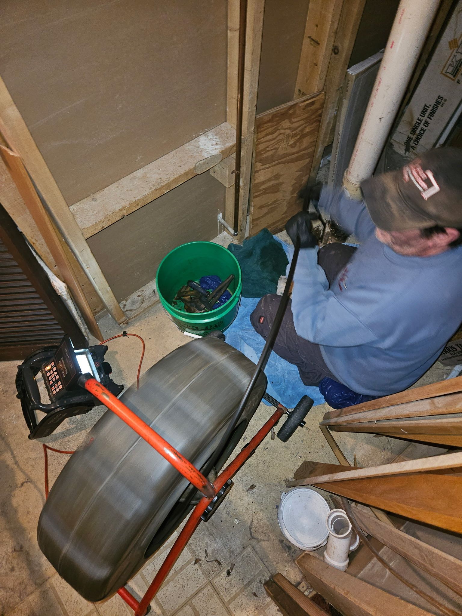 A man is working on a drain in a basement.
