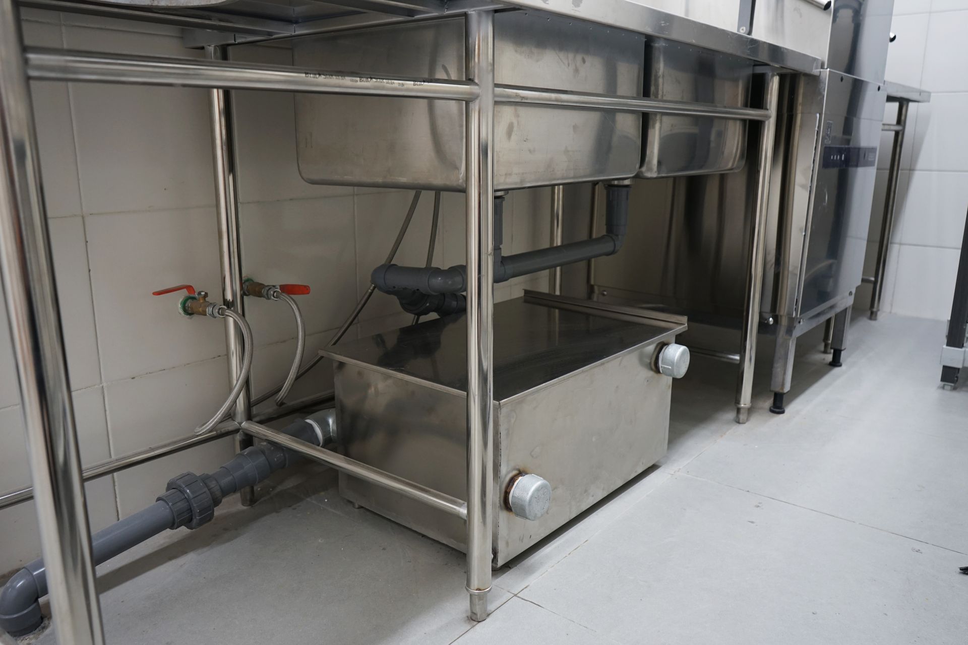 Stainless steel industrial tank and pipes in a clean utility room