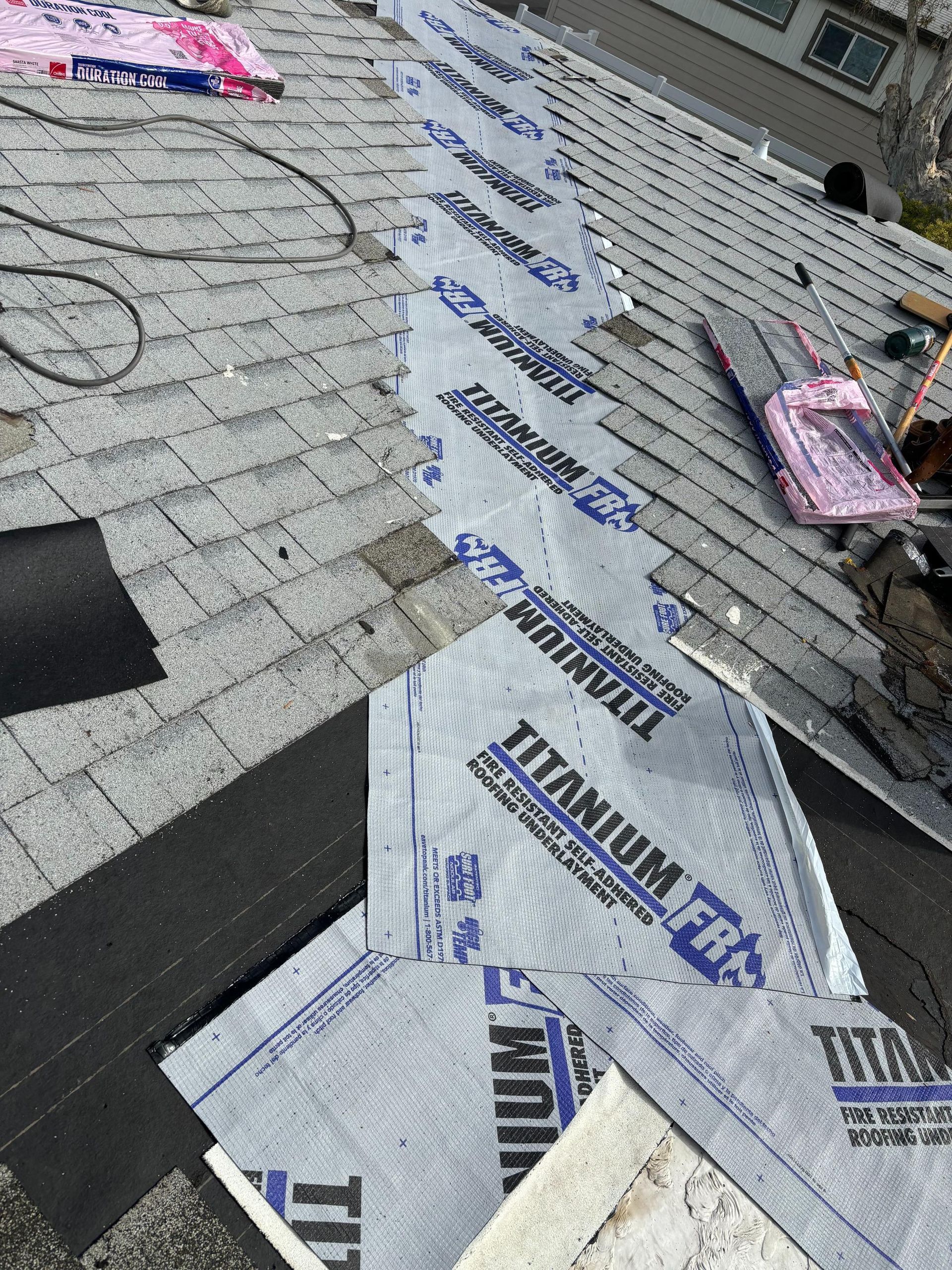 Roof with shingles being repaired, showing underlayment and roofing materials.