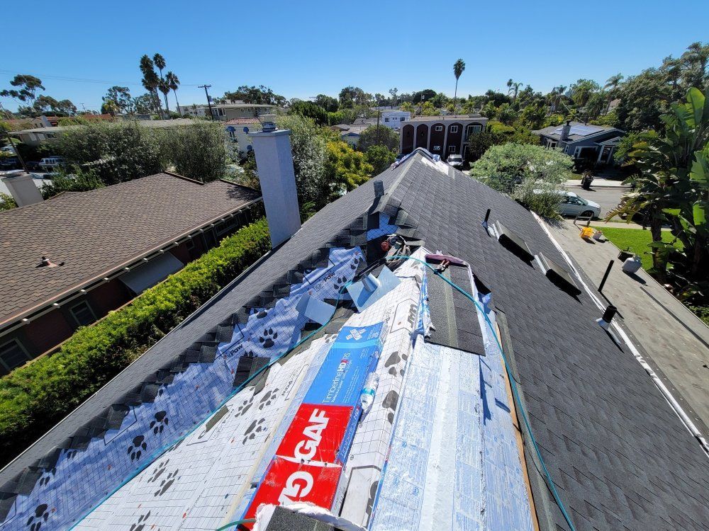 Roof with shingles being repaired, showing underlayment and roofing materials.