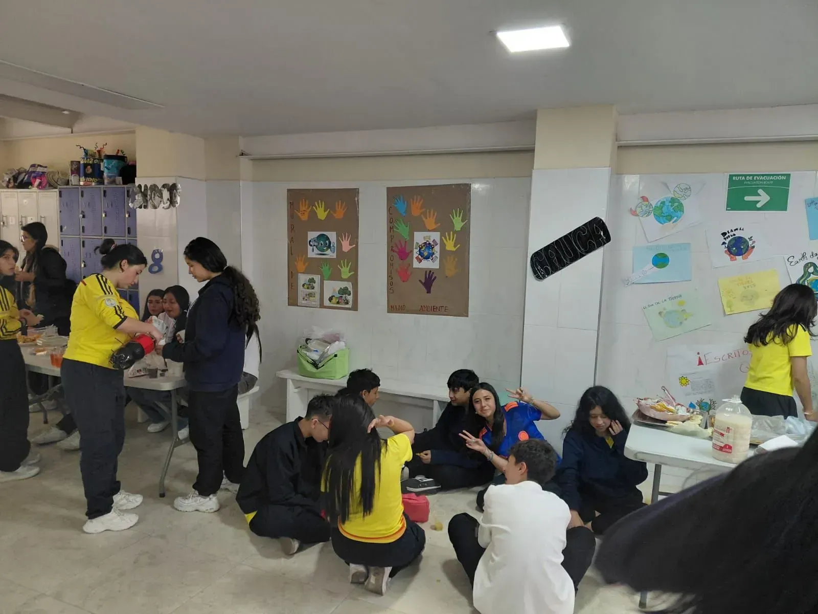 Los estudiantes se reunieron en un aula, charlando y trabajando en mesas con coloridos carteles en las paredes.