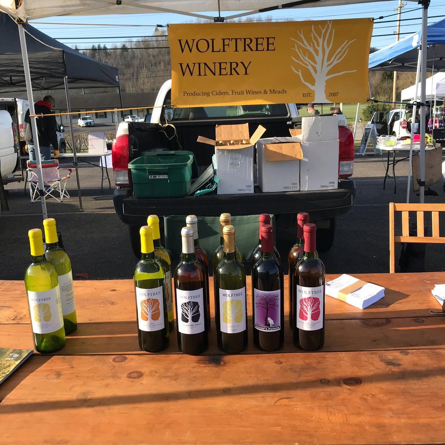 Wolftree Winery booth with wine bottles displayed on a table at an outdoor market.