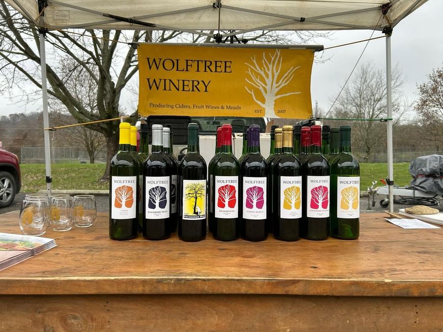 Wolftree Winery wine bottles displayed on a wooden table under a tent at an outdoor market