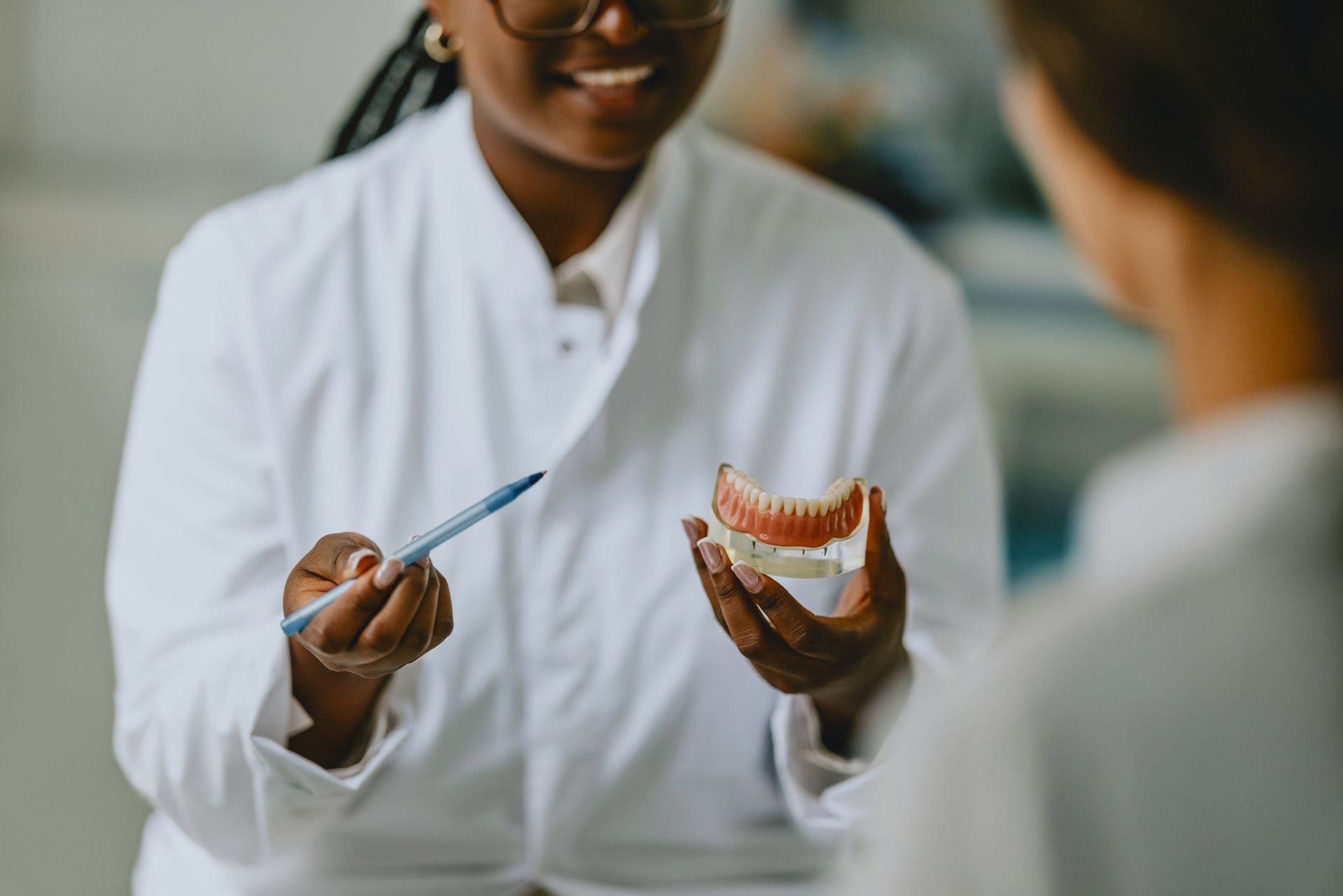 Dentist Explaining Dental Procedure Using Denture Model