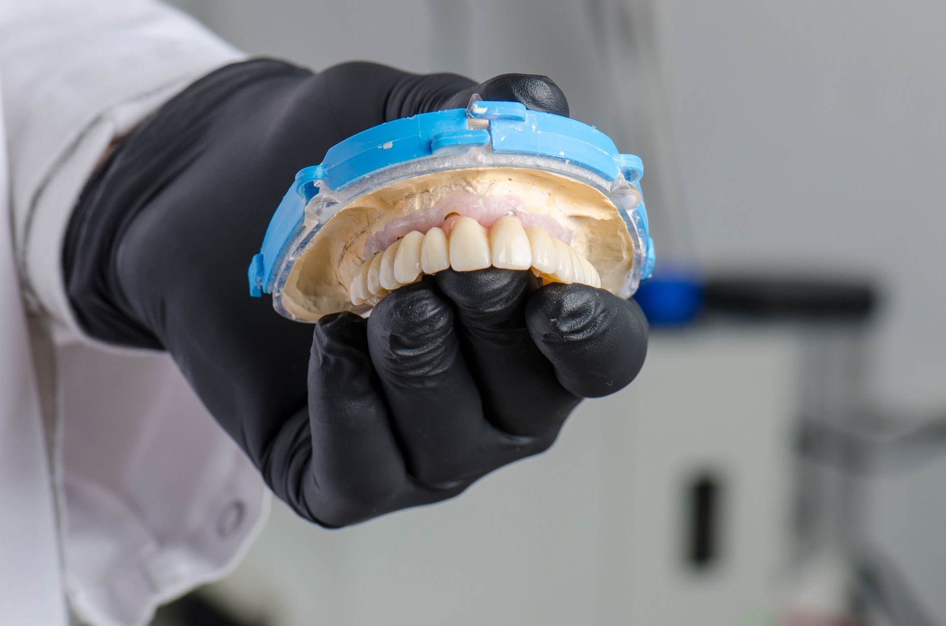 Dentist at Dentures In A Day in Grand Rapids, MI, holding a full denture, showcasing quality tooth r