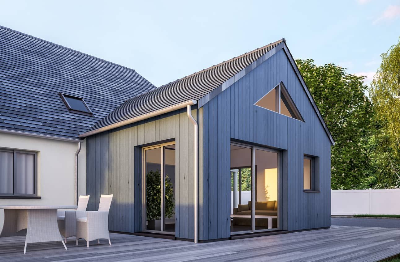 Extension moderne de maison bleu-gris avec de grandes fenêtres et un petit patio à côté d'une maison blanche