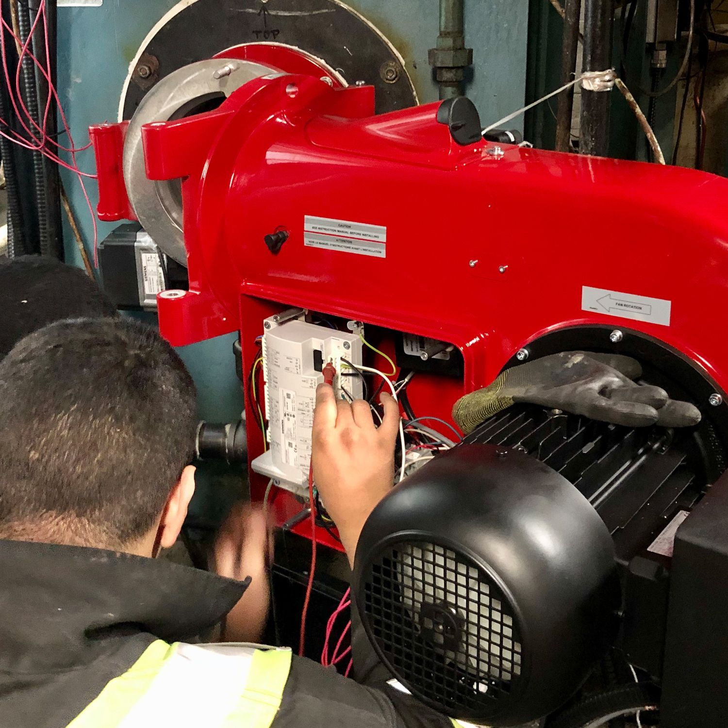 A man is working on a red machine in a factory.