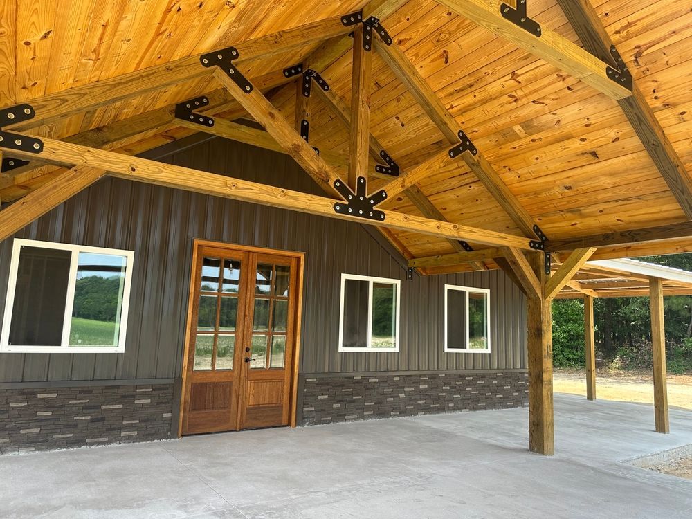 Brown building with wooden beams, doors, and windows under a canopy. A concrete patio is in front.
