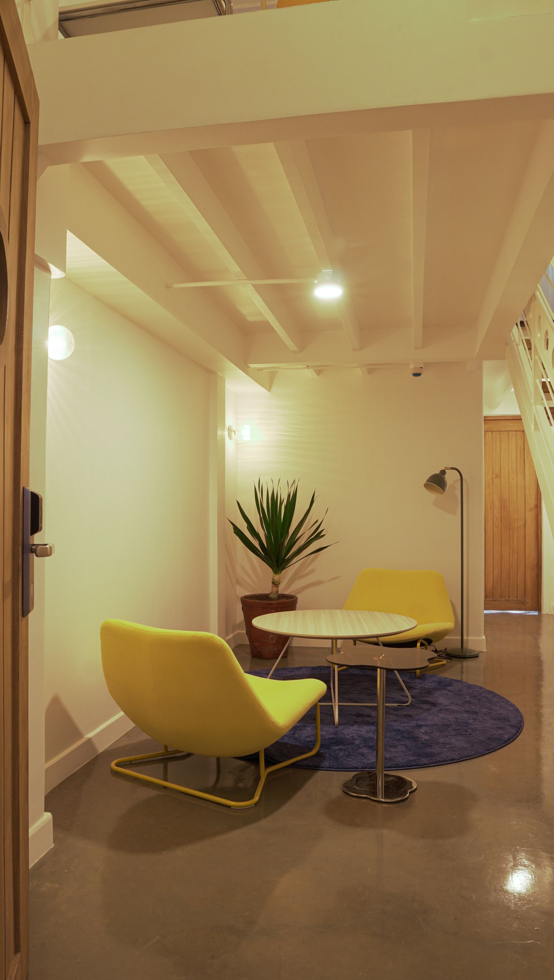 Yellow chairs and round table on blue rug in a bright, modern sitting area.