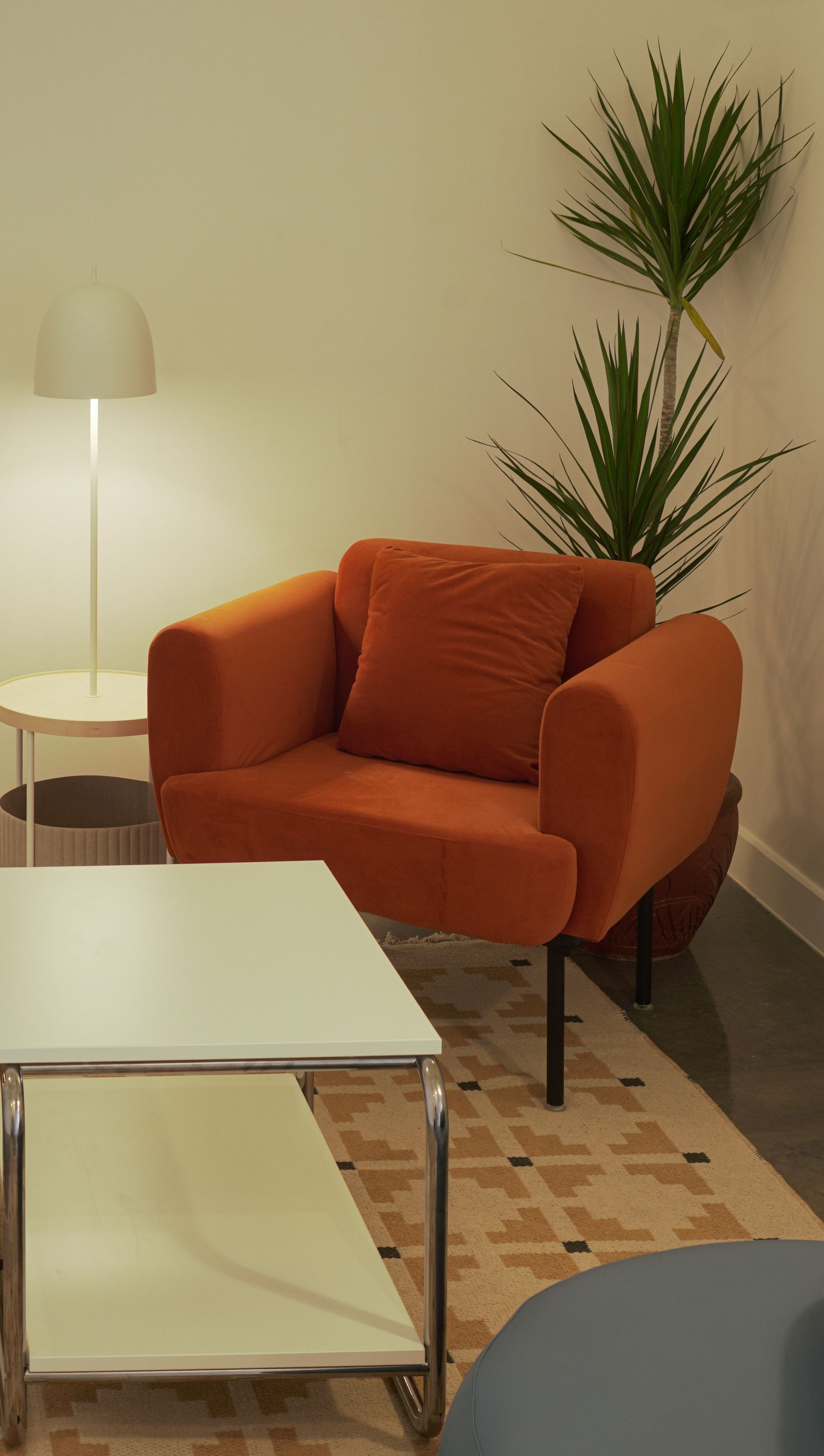 Orange armchair, side table, floor lamp, and a plant in a cozy living room.