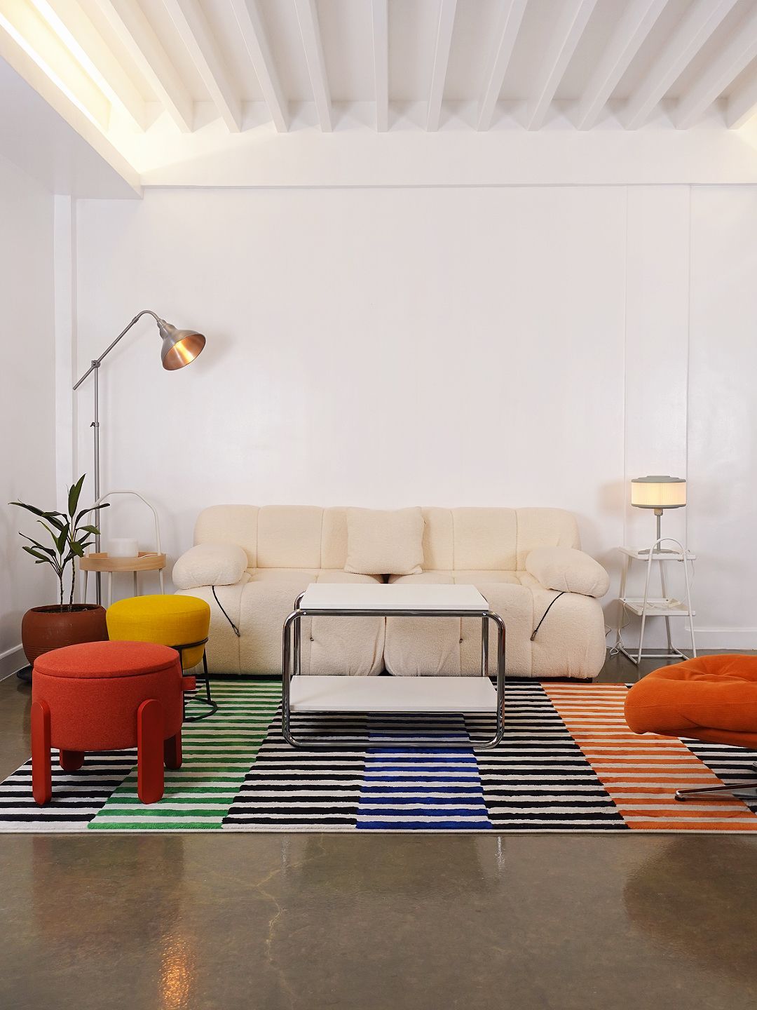 Living room with cream sofa, colorful rug, modern furniture, and a floor lamp.