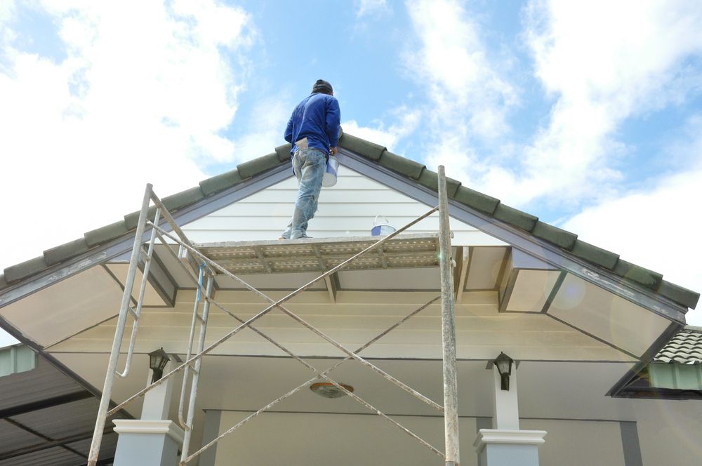 A Man is Standing on a Scaffolding on Top of a House — Sheps Roofing Service Pty Ltd In Albion Park Rail, NSW
