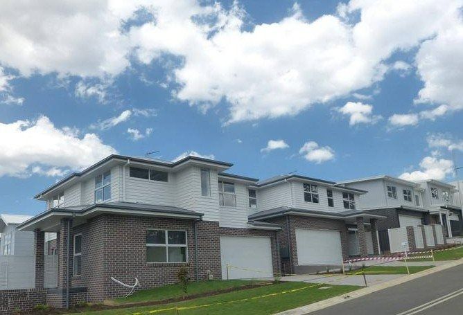 A Row of Houses on a Hill With a Blue Sky in the Background — Sheps Roofing Service Pty Ltd In Albion Park Rail, NSW