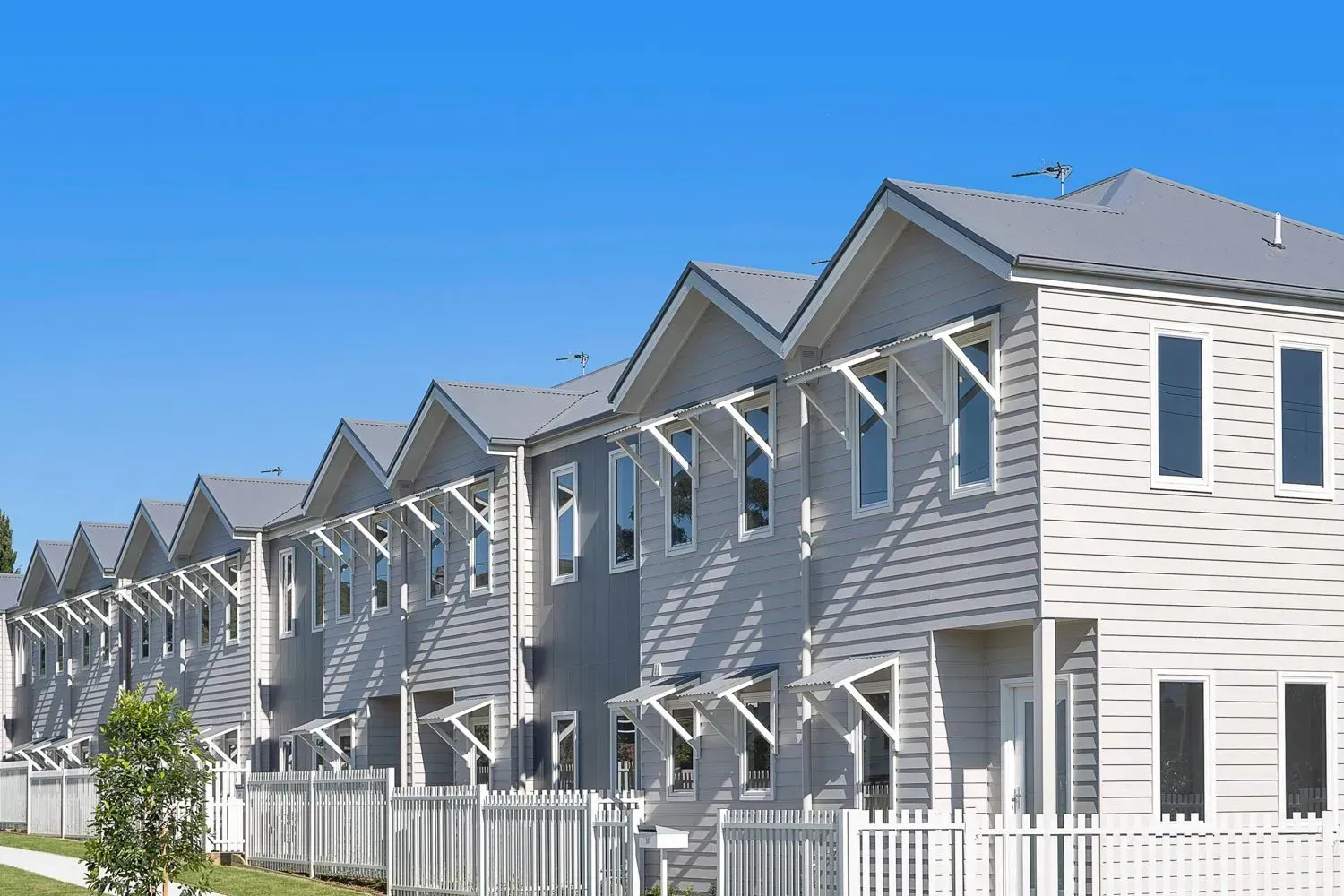 A Row of Houses With a White Fence — Sheps Roofing Service Pty Ltd In Albion Park, NSW