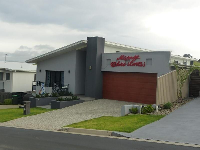 A House With a Red Garage Door and a Sign That Says Happy Holidays — Sheps Roofing Service Pty Ltd In Wollongong, NSW