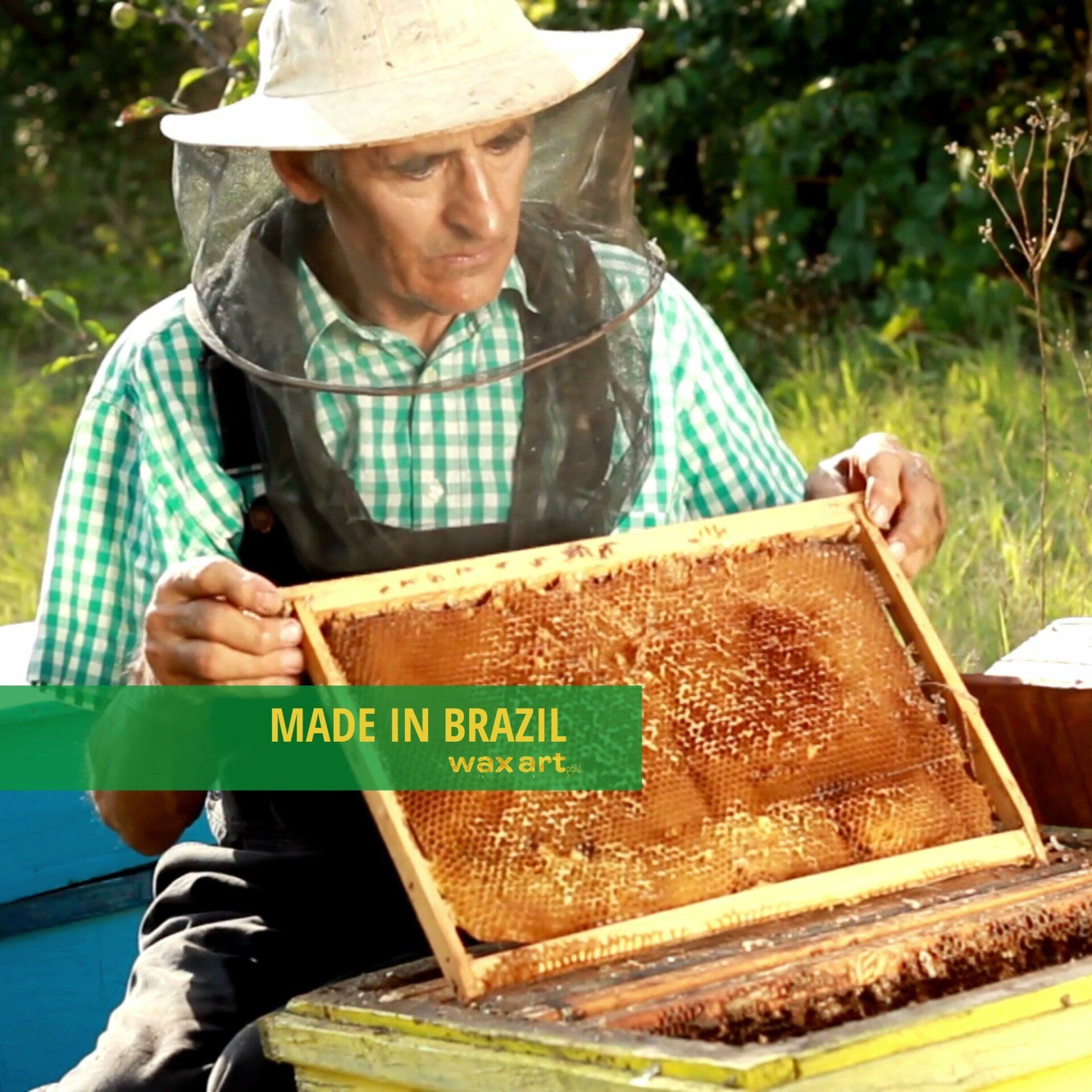 Imker in Schutzkleidung hält eine Honigwabe mit dem Etikett „Made in Brazil“.