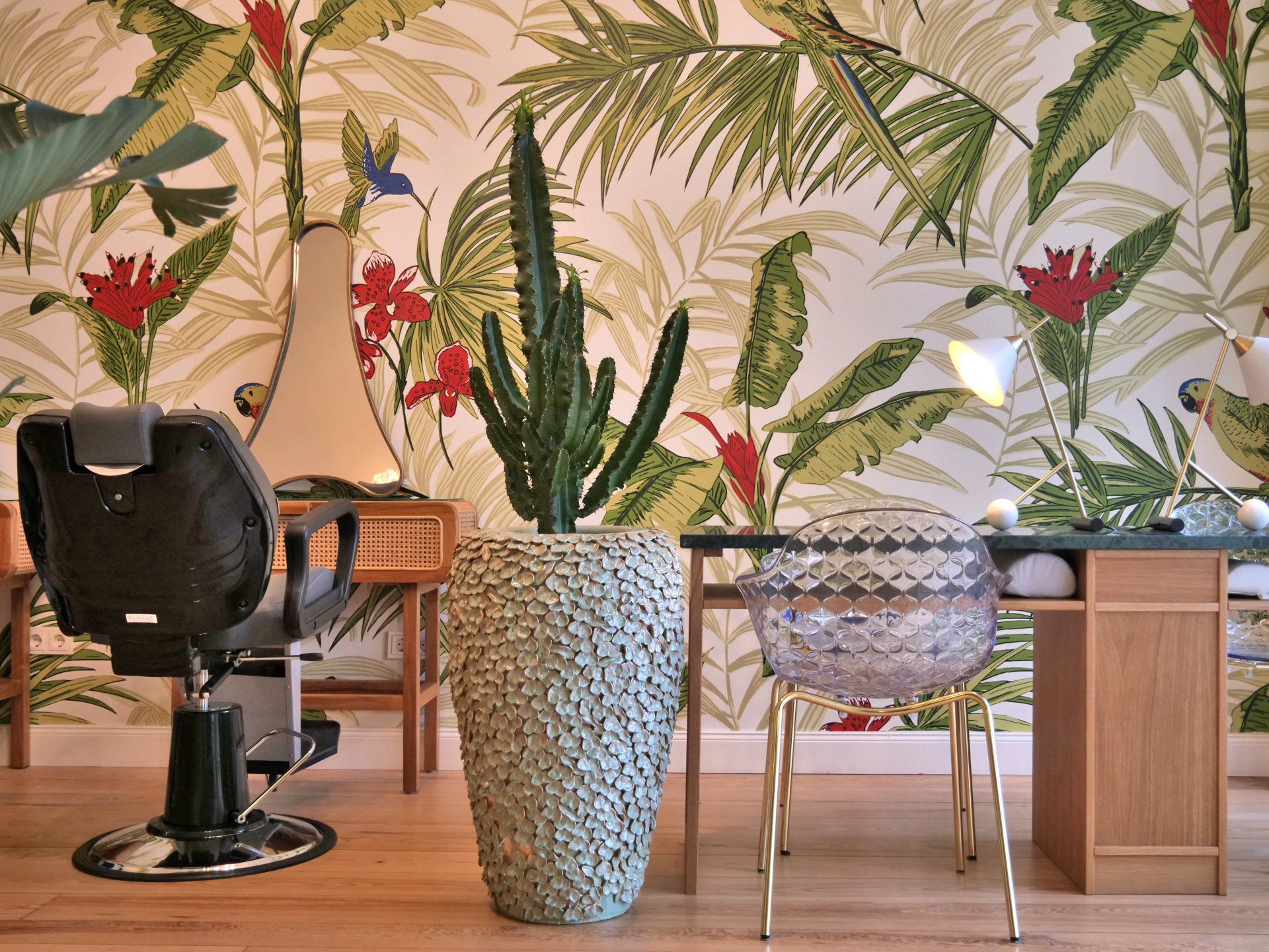 Interieur eines Friseursalons mit tropischer Tapete, Kaktus und Friseurstuhl.