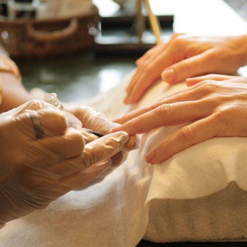 Eine Maniküristin lackiert einer Kundin im Salon die Fingernägel.