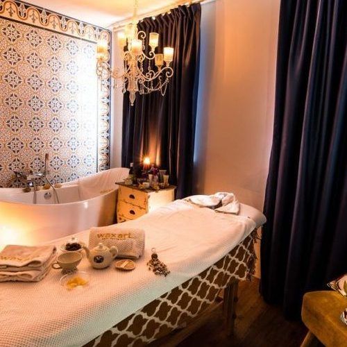 Massage-Spa-Raum mit Massageliege, Badewanne und blau-weiß gefliester Wand.
