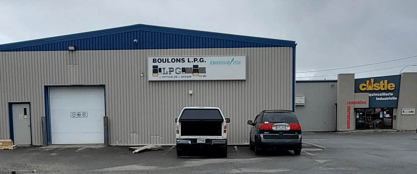 Vue extérieure de deux bâtiments industriels. L'un d'eux possède une porte blanche et une enseigne « Broders Auto Parts ». À côté se trouve un bâtiment portant l'inscription « clectila ».