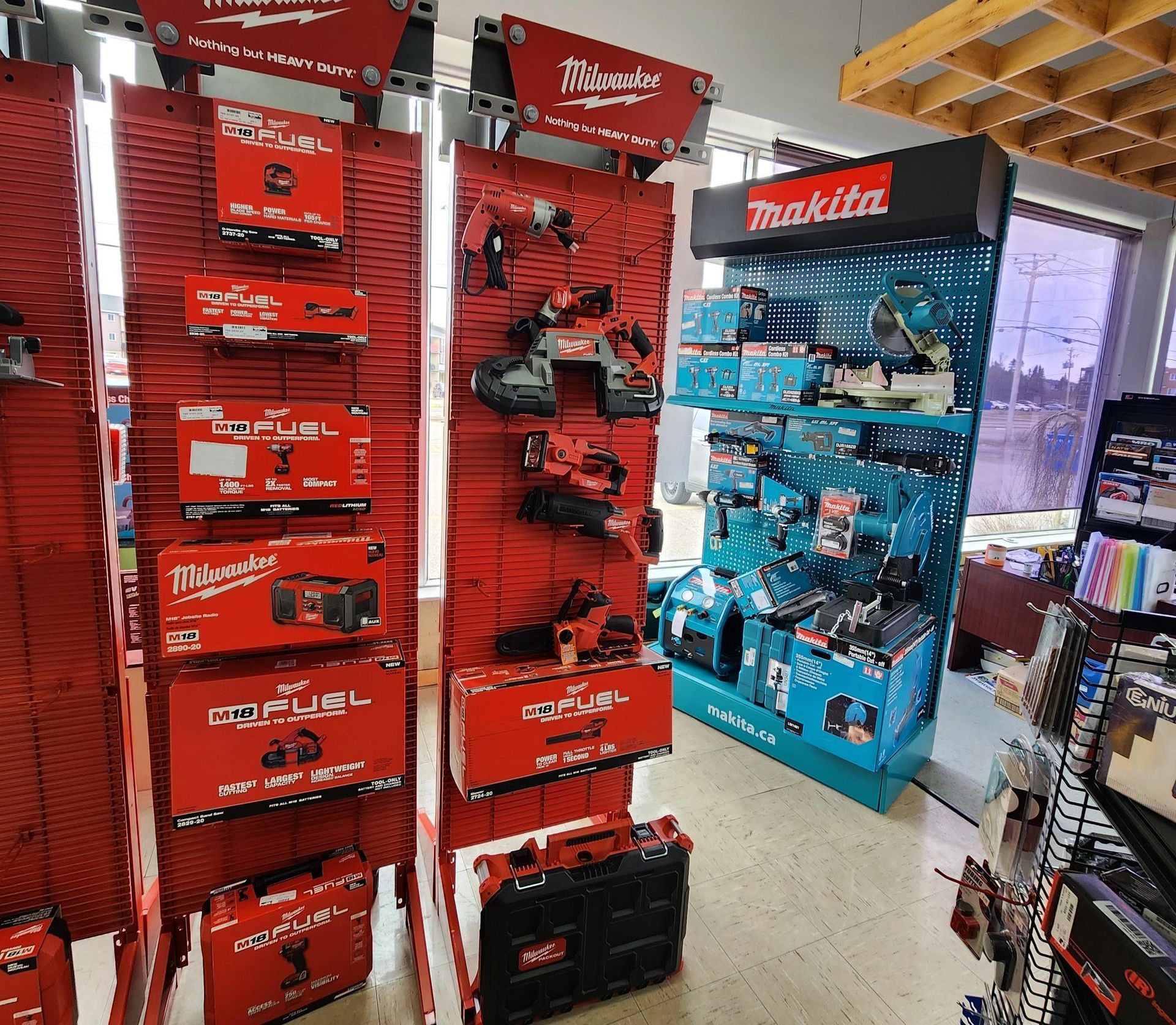 Présentoirs d'outils en magasin, marques Milwaukee et Makita, emballages rouges et bleus sur les étagères.