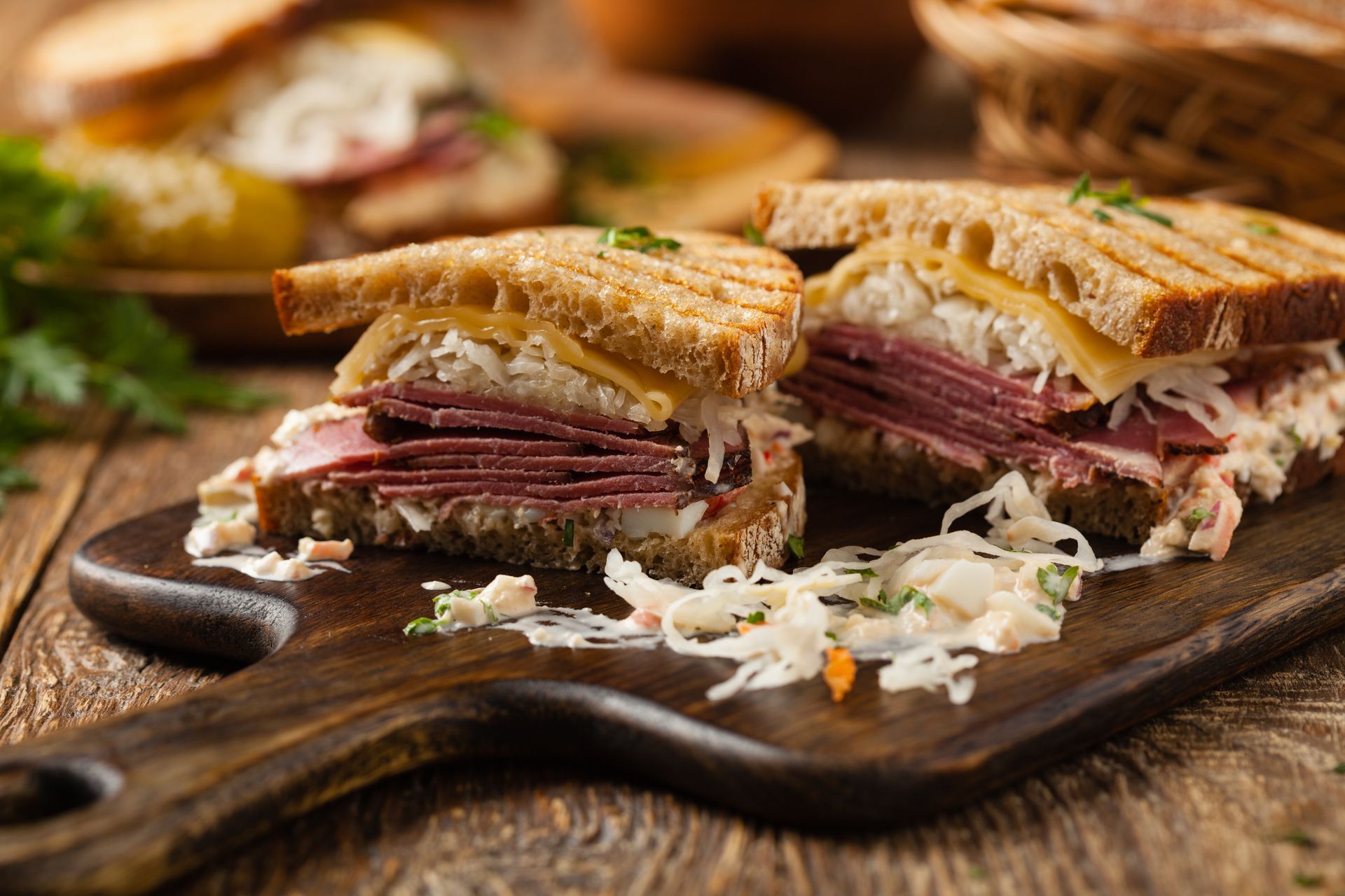 Reuben sandwich on a wooden board; corned beef, Swiss cheese, sauerkraut, toasted rye bread.