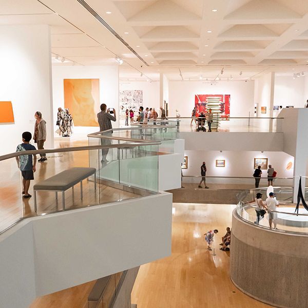 People viewing art in a modern museum with multiple levels and white walls.