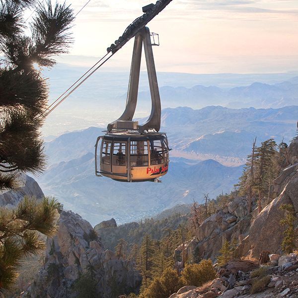 Cable car ascending a mountain, offering scenic views of surrounding peaks.