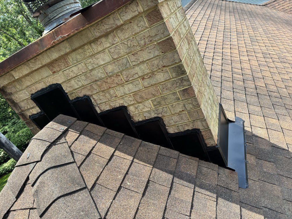 Roof shingles and a brick chimney flashing detail on a house exterior