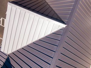 Close-up of overlapping white and gray metal roof panels with diagonal lines.