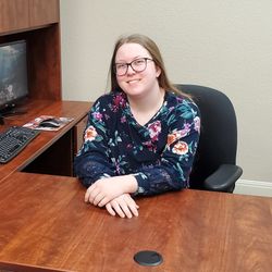 NATALIE HENDERSON Natalie Henderson, sitting at a desk.