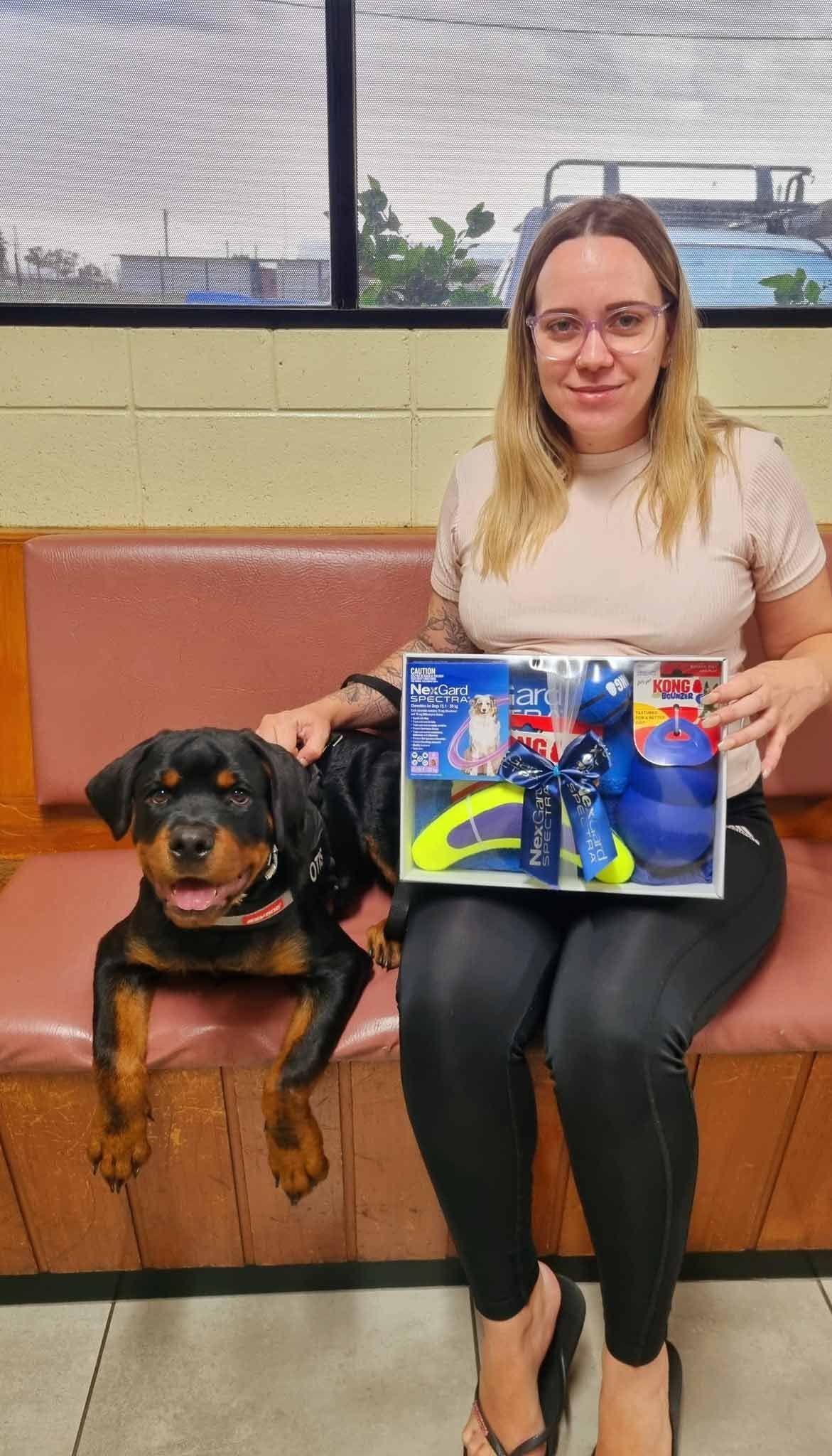 A Woman Is Sitting On A Bench Holding A Picture Of A Dog — Mount Isa Veterinary Surgery In Ryan, QLD