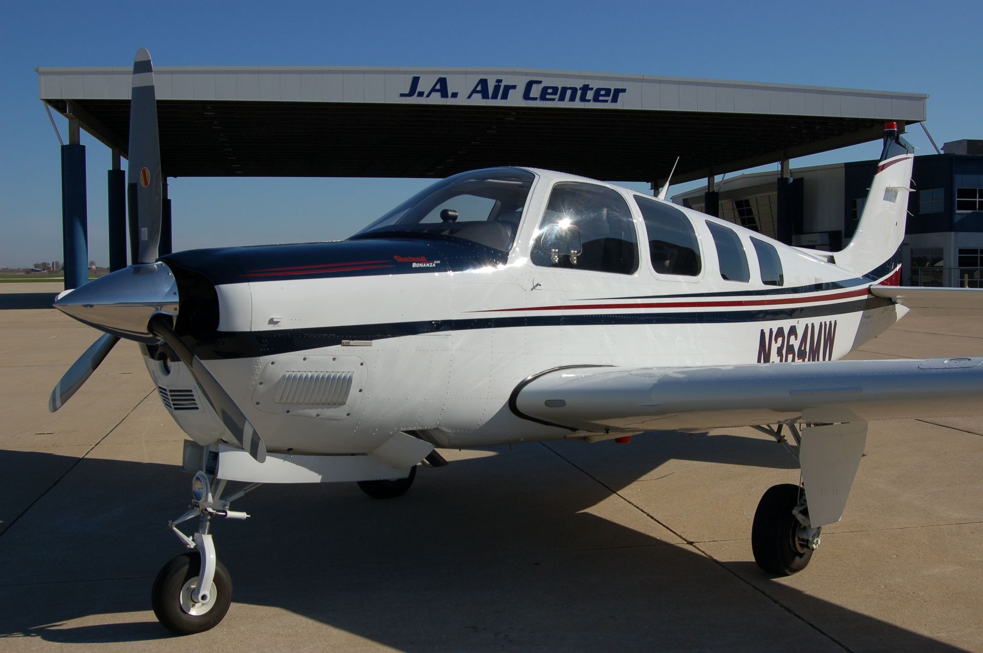 Beechcraft Bonanza aircraft parked outside the J.A. Air Center on a clear day.