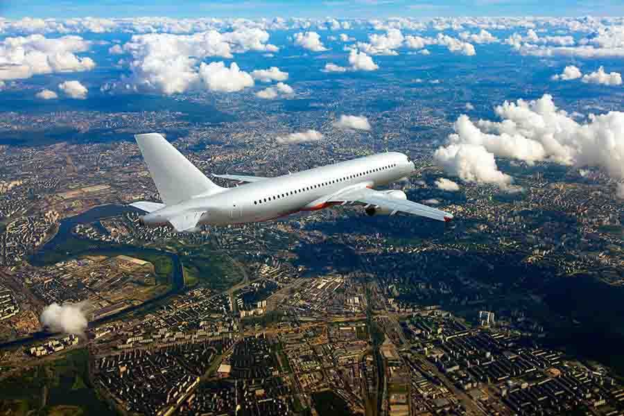 Commercial passenger jet flying above city skyline at cruising altitude.