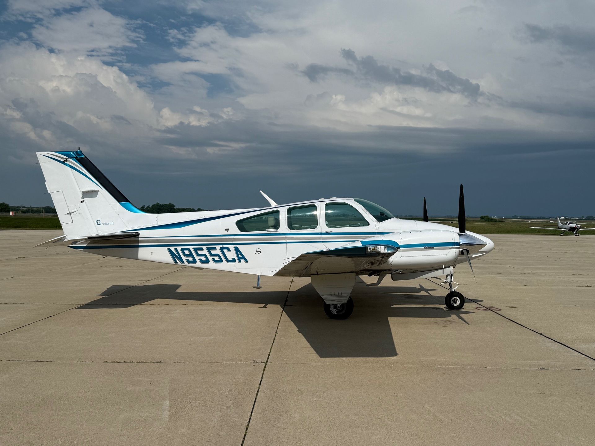 Beechcraft Baron twin-engine training aircraft parked on the ramp under cloudy skies.