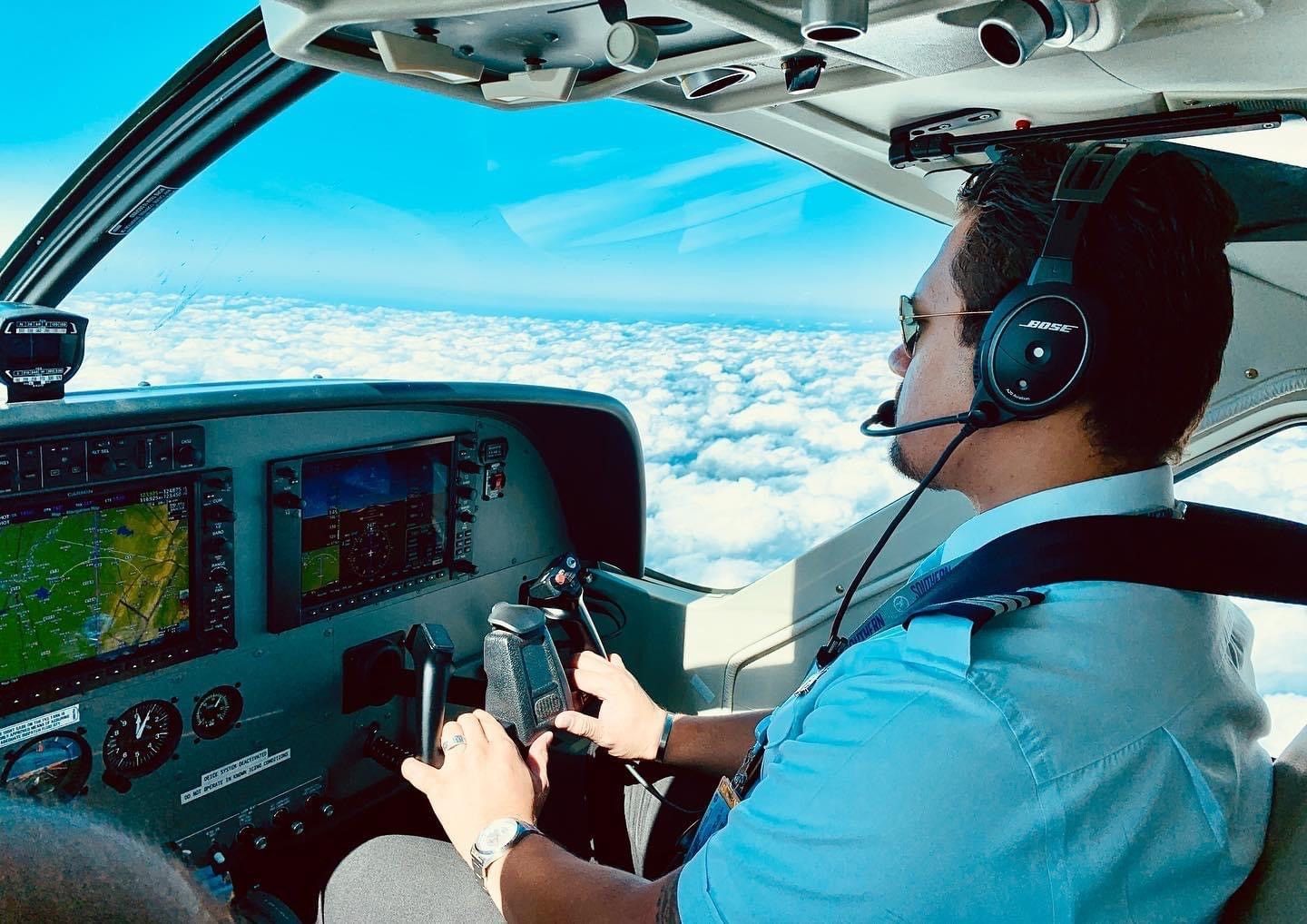 Pilot flying glass cockpit aircraft above clouds.