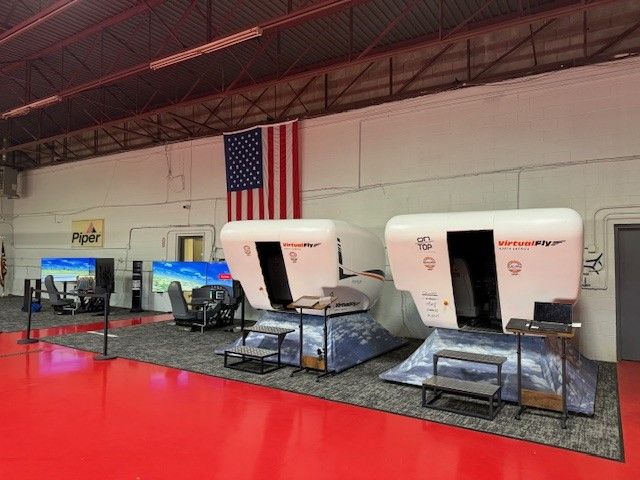 Indoor shooting range with three white target pods and an American flag on the wall