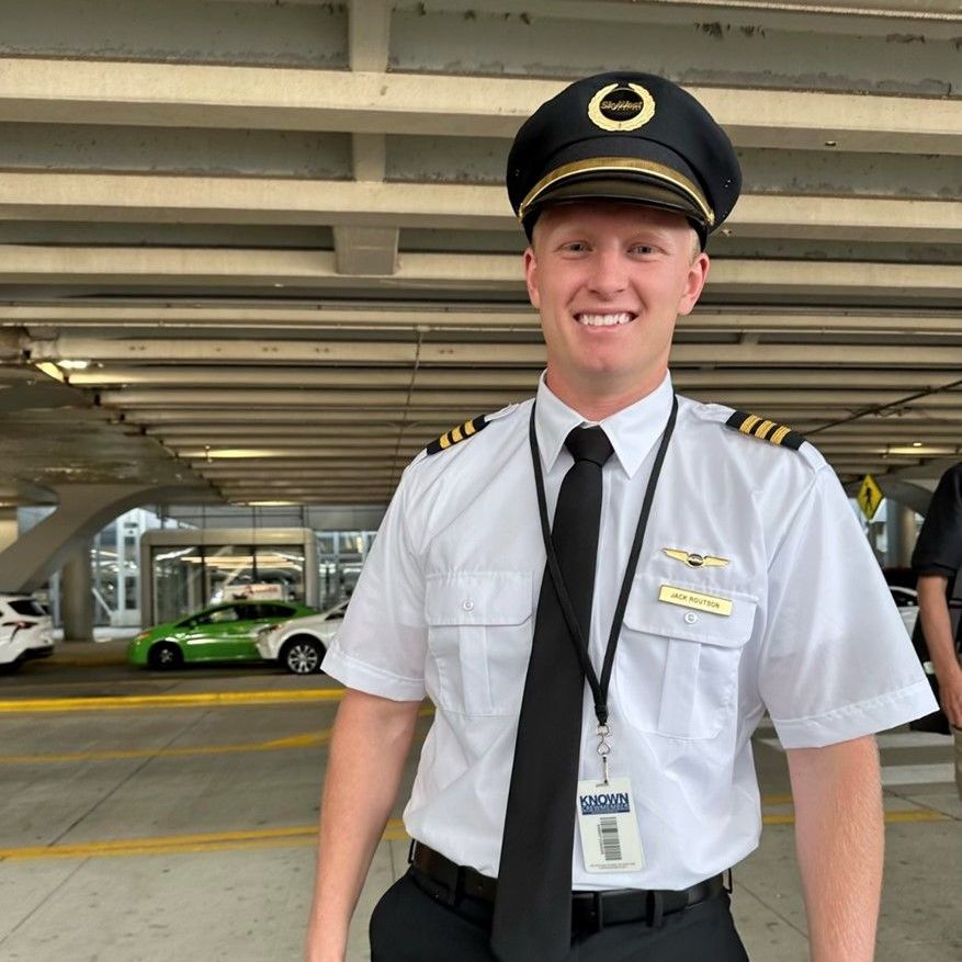 Airline pilot in uniform standing outside airport terminal before commercial flight.