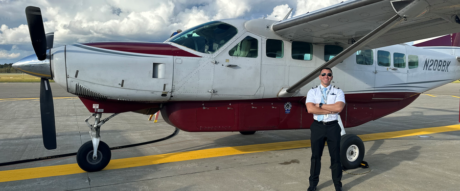 Professional pilot standing beside single-engine turboprop aircraft on airport ramp