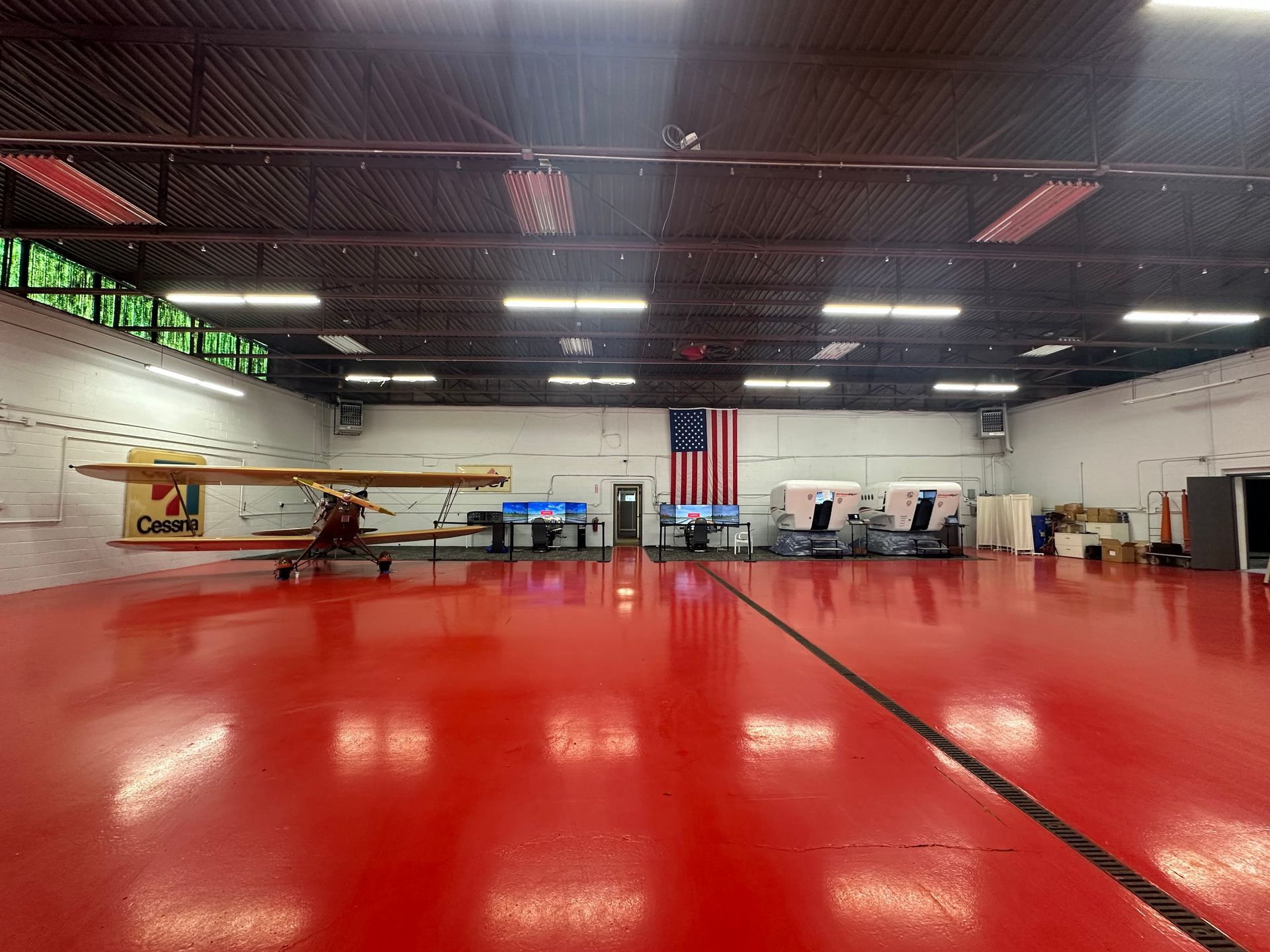 Indoor martial arts gym with a red mat floor, wall mirrors, training equipment, and a U.S. flag.