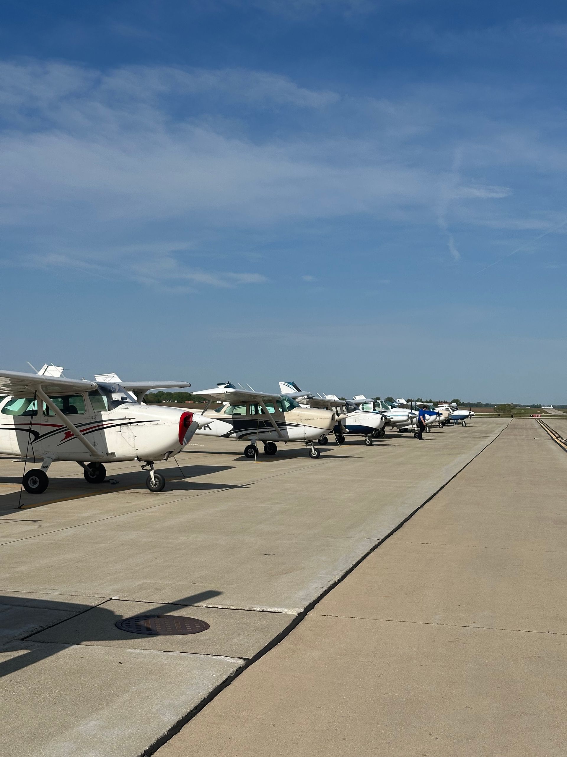 Rows of small airplanes parked on a runway under a clear blue sky